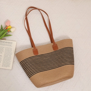 Detail van de handgeweven rieten tas met zwarte strepen en bruine leren riemen