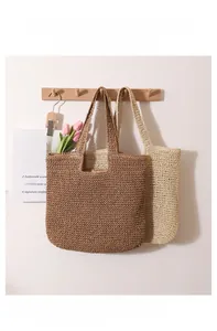 Close-up of hand-woven straw tote bag texture and integrated handle in indoor setting
