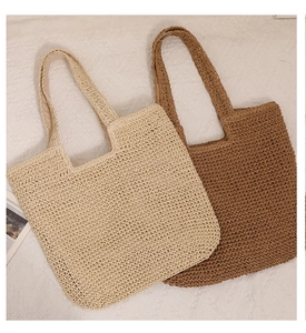 Close-up of beige and brown handmade woven straw tote bags with detailed grid texture