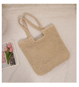 Detail of hand-woven cream straw tote bag with wide straps on a French aesthetic background