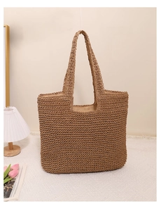 Detail of hand-woven straw tote bag with fabric lining and sturdy handles in a cozy setting