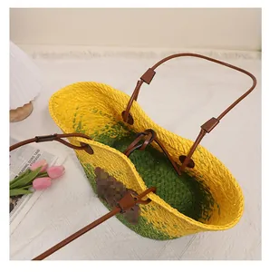 Vue détaillée d'un sac cabas en paille tressée jaune et vert avec anses en cuir marron