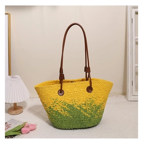 Détail du sac cabas en paille dégradé jaune-vert avec anses en cuir marron et décor d'été
