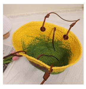 Détail du sac cabas en paille tressée avec contraste jaune-vert et anses en cuir