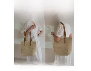 Detail showing versatile carrying options for a beige straw tote with brown leather handles