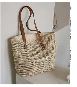 Detail of woven straw tote bag featuring brown leather handles and secure top zipper closure