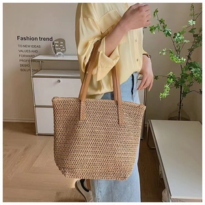Close-up of woven straw tote bag featuring brown leather handles and fine texture