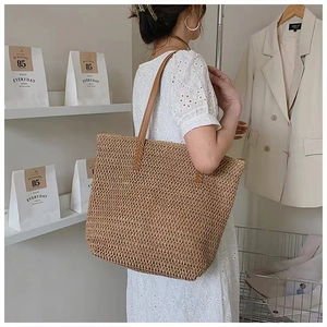 Detail showing the woven texture of the large straw tote with brown leather handles