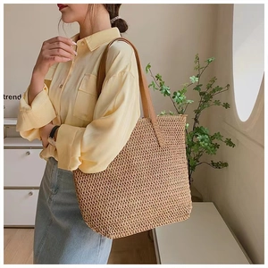 Detail of hand-woven straw shoulder bag with brown leather straps for summer vacations