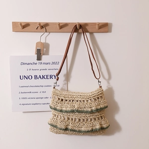 Sac en paille bohème avec volants verts et bandoulière en cuir sur cintre en bois