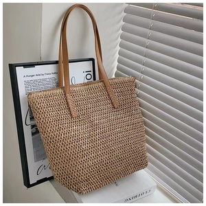 Detail of hand-woven straw tote with brown leather handles by a sunny window
