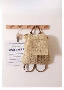 Close-up of the hollow crochet weave texture and brown leather straps on the straw backpack