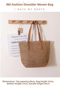 Straw tote bag detail hanging on hook with leather straps and natural woven texture