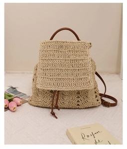 Detail of hollow woven straw backpack with brown faux leather straps and drawstring closure