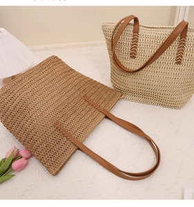 Detail of woven straw tote bag handles and zipper closure in brown and cream colors