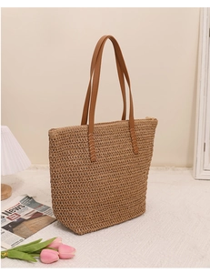 Detailed macro view of woven paper straw texture and brown leather strap on tote bag