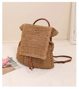 Detailed texture of hollow woven straw backpack with brown leather drawstrings and handle