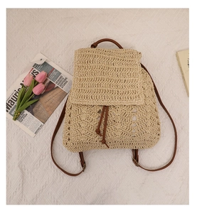 Detail of hollow woven straw backpack with brown leather straps and drawstring closure