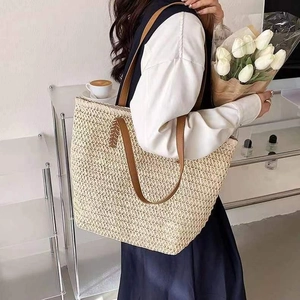 Minimalist straw tote bag with brown leather handles for summer beach vacations