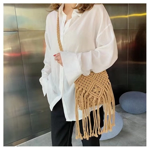 Detail of bohemian handmade woven straw crossbody bag with elegant tassels on a model