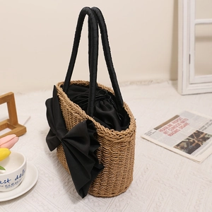 Handmade straw woven tote bag with large black bow and drawstring lining for beach