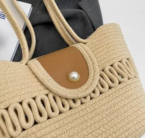 Detail van beige geweven tas met bruine lederen flap en een parelsluiting