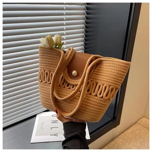 Detail van de karamelkleurige gehaakte strandtas met golfpatroon en parelsluiting