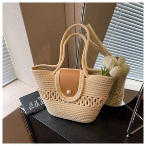 Detail van beige gehaakte strandtas met bruine lederen flap en grote parelsluiting