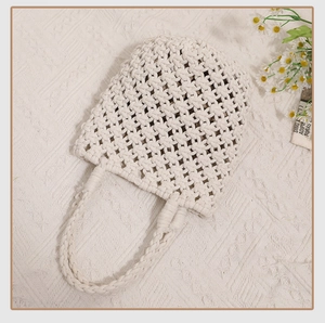 Detailed close-up of cream woven cotton rope handbag with intricate mesh hollow-out pattern