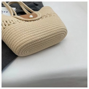 Detail van handgeweven katoenen textuur met parelsluiting op een beige vakantie strandtas