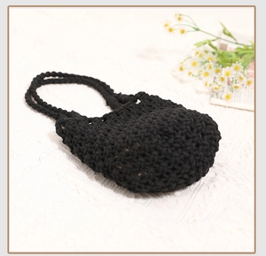 Detail of black crochet cotton weave pattern and handles on a handmade summer beach tote