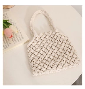 Detail of hollow star-patterned crochet knit beach bag on table with tulips