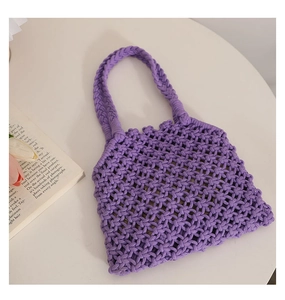 Detail of purple hollow knit cotton rope tote bag with wide braided handle on white surface