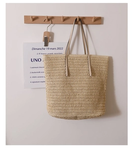 Close-up of large straw tote bag featuring tight woven texture and beige leather handles