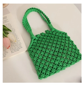 Detail of green handmade woven tote bag with hollow mesh texture on a white table