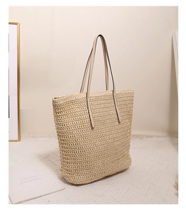 Detailed close-up of woven paper straw texture and white leather strap of the tote bag