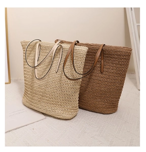 Detail of woven straw tote bags in beige and brown with leather straps for summer vacations