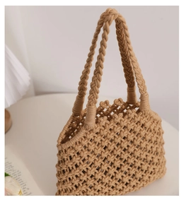 Close-up of khaki woven cotton rope bag with hollow geometric texture on a white table