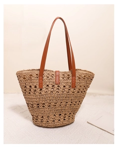 Detail of hollow-out straw weave tote with brown leather handles for beach vacation