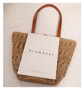 Detailed top-down view of woven hollow beach tote bag with brown faux leather straps