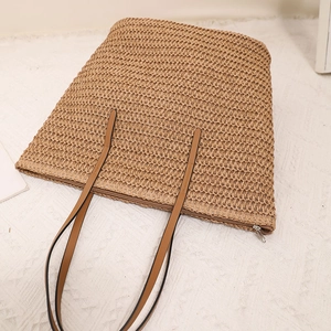 Minimalist straw tote bag with brown straps and zipper closure for summer beach vacation