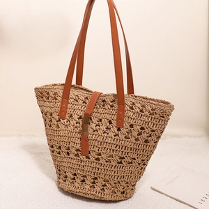 Large hollow woven straw tote bag with brown leather handles for beach vacation style