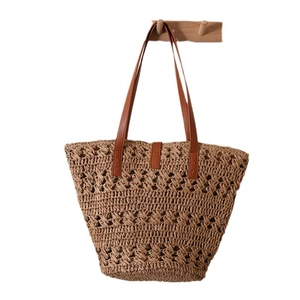 Handwoven straw tote bag with brown leather handles and hollow mesh design for beach vacation