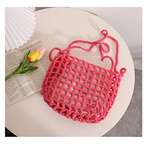 Detail of pink hollow crochet tote bag with woven mesh pattern and long shoulder strap