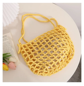 Detail of yellow hollow knit cotton beach bag with cream fabric lining on a round table