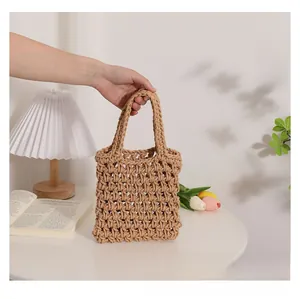 Detail of a handmade hollow woven cotton tote bag in light brown held by hand