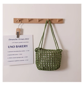 Detailed view of green crochet mesh bag with white inner lining on a wooden hook