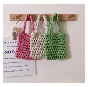 Close-up of three woven cotton hand bags in green, white and pink with net pattern