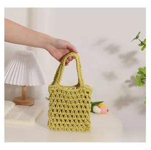 Detailed texture of yellow woven cotton mesh handbag on a white table with floral decor