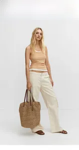 Detail of the hollow crochet weave and leather straps on the brown straw beach tote bag